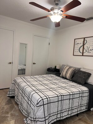 A bedroom with a bed, a ceiling fan, a wall-mounted light, a framed quote, and a mirror. - Beautiful 3-bedroom townhome with AC in wonderful Jacksonville (Jacksonville)