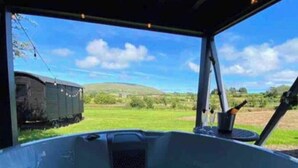 Un jacuzzi con vistas a un paisaje verde y un tren al fondo.