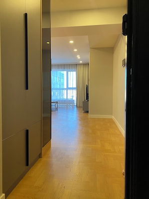 A hallway with wooden flooring, a glass partition, and a view of a balcony with curtains. - Cozy Apartment in Ulaanbaatar City Center, Near Shangri-La (Ulaanbaatar)
