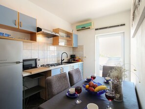 Eine kleine Küche mit Essbereich, Kühlschrank, Herd und Mikrowelle.