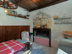 Ein rustikales Interieur mit Kamin aus Stein, Holzbalken und karierter Tischdecke.