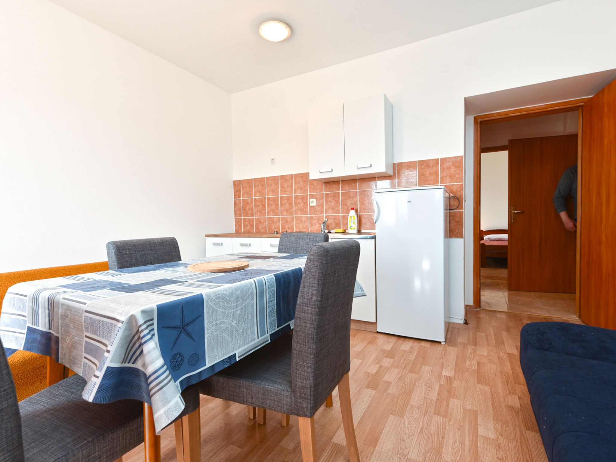 A compact living space with a dining area, kitchenette, and a door leading to a bedroom.