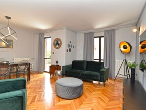 A modern living room with a green sofa, a round ottoman, a dining table with chairs, and a large window with curtains. - House 843 by Interhome (Fažana)