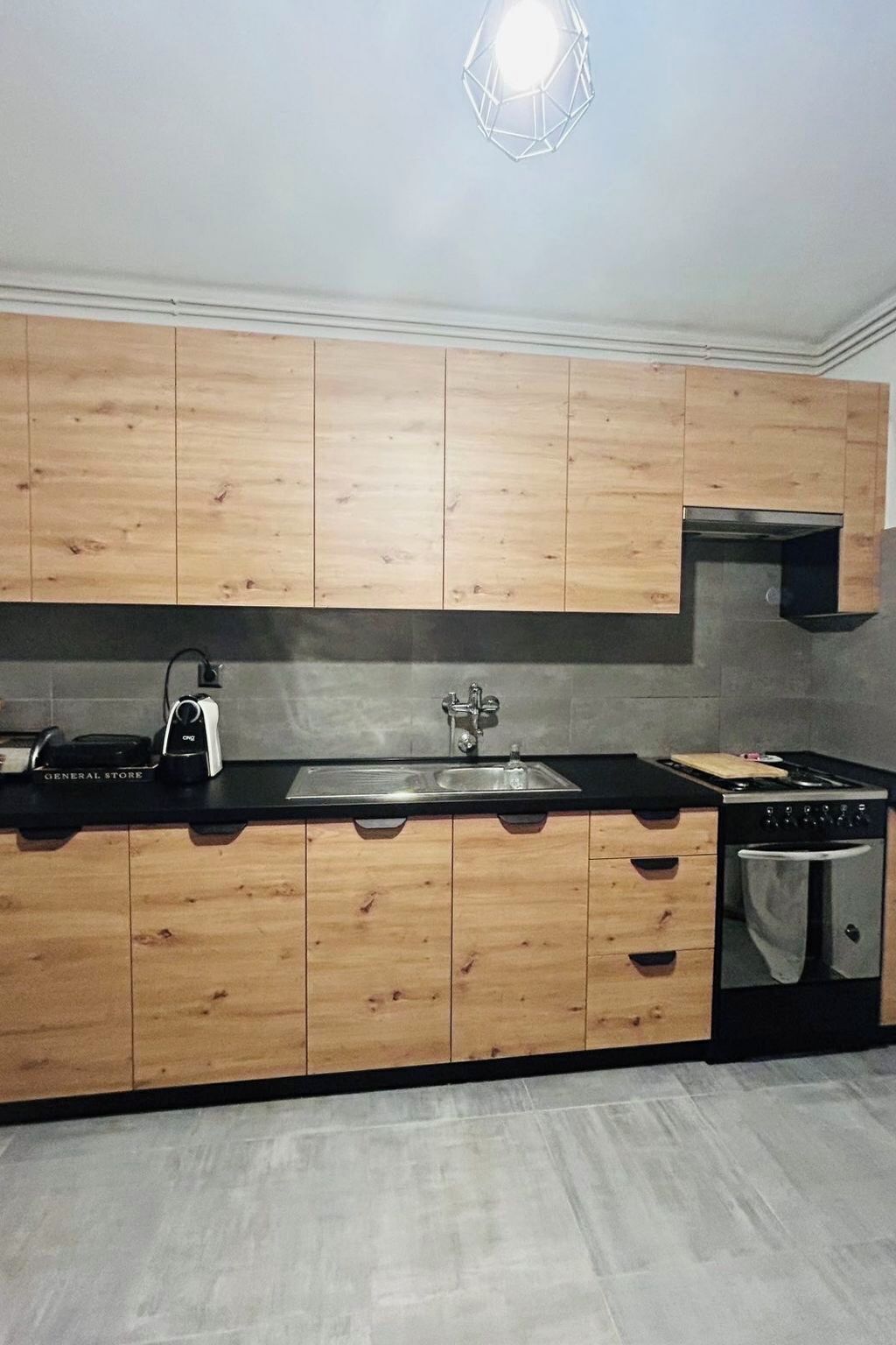Una cuina moderna amb armaris de fusta, una taulell de nitram, un rentaplat i una placa de cocció.