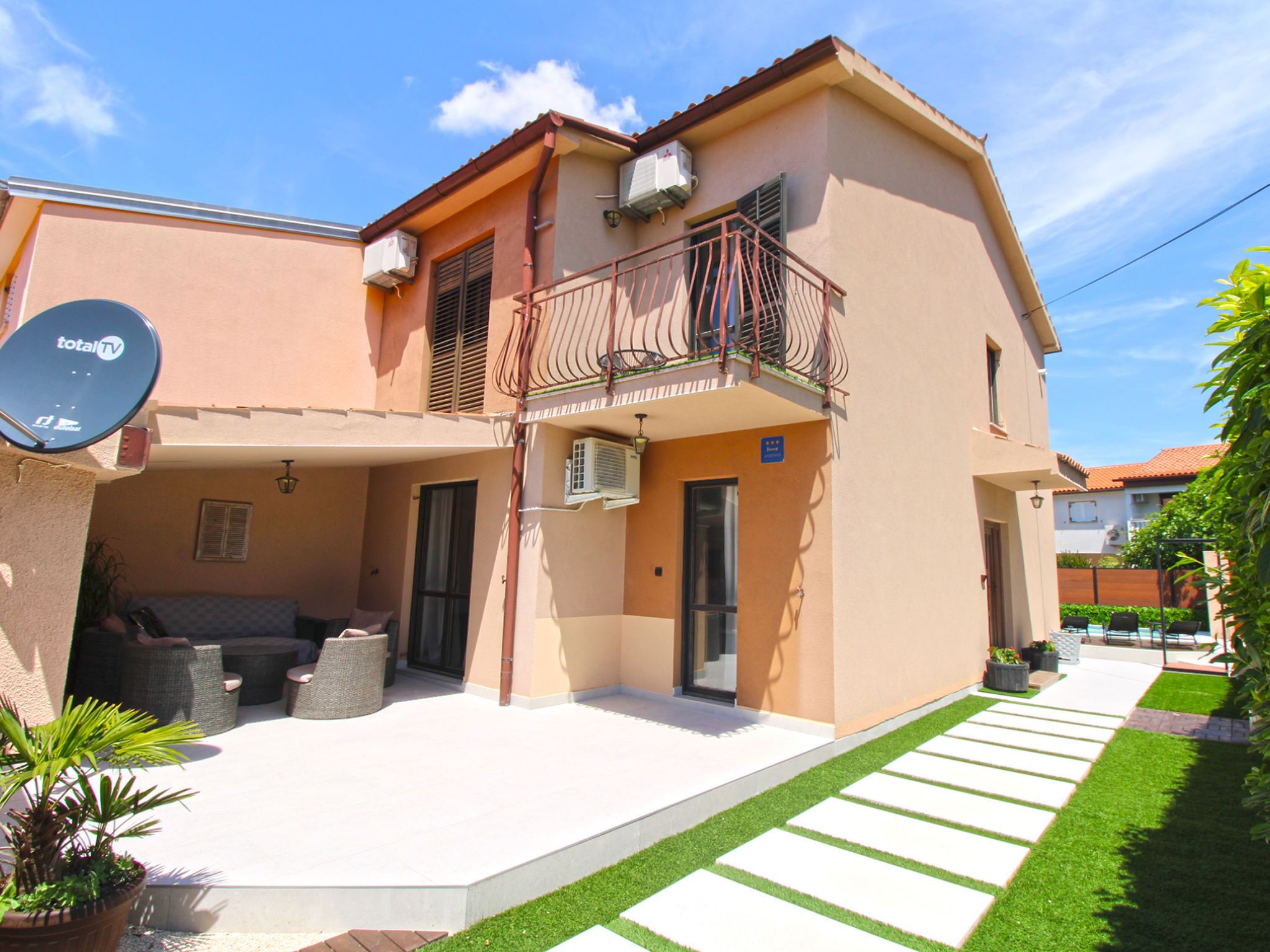 A two-story building with a balcony, outdoor seating, and a satellite dish.