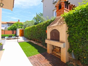 A patio area with a brick pathway, a small garden, and a brick oven structure. - House 843 by Interhome (Fažana)