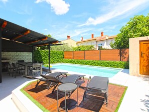 A backyard with a swimming pool, outdoor furniture, and a covered patio area. - House 843 by Interhome (Fažana)