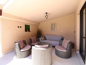 A sunlit patio with wicker furniture, a ceiling fan, and a small window with a plant. - House 843 by Interhome (Fažana)