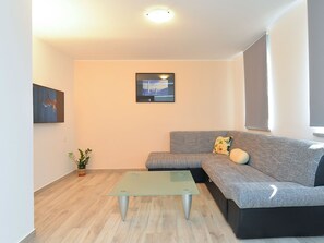 Ein modernes Wohnzimmer mit einem Glastisch, einem grauen Sofa und einem Stadtbild an der Wand.