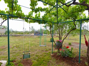 A garden with a swing set, a hanging planter, and a tree. - House 1691 by Interhome (Fažana)