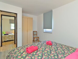 A bedroom with a bed, a chair, a wardrobe, and a window with a blind. - House 1691 by Interhome (Fažana)