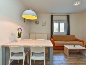 A modern living room with a dining area, a sofa, a coffee table, and a potted orchid. - Apartment 2299 by Interhome (Fažana)