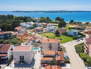 Zona residencial a la costa, amb una barreja d'arquitectura moderna i tradicional, vistes clares al mar i un espai central oberta amb una piscina.