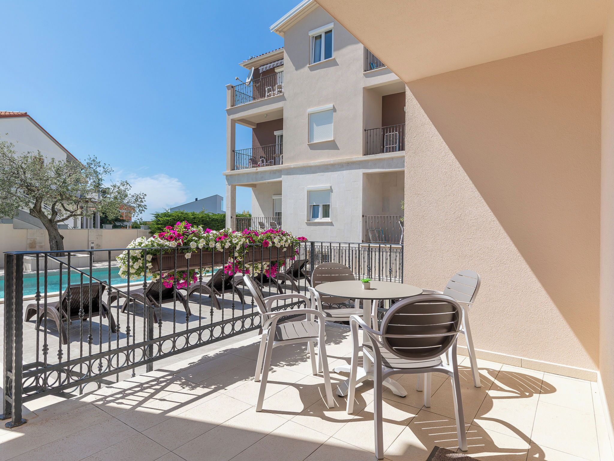 A balcony with a pool, outdoor furniture, and a view of a building.