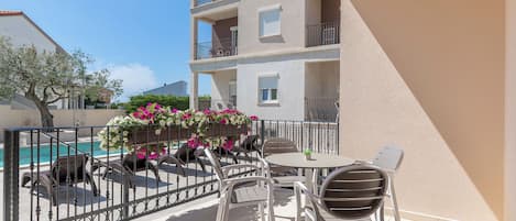 A balcony with a pool, outdoor furniture, and a view of a building.