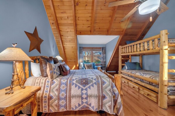 A cozy bedroom with a wooden bunk bed, a large bed with patterned bedding, a star decoration, and a lamp. - 8 Bed 5 Bath Luxury Lodge-Free Resort Shuttle, HotTub, Sauna, Game Room, Theater (Sugar Mountain)