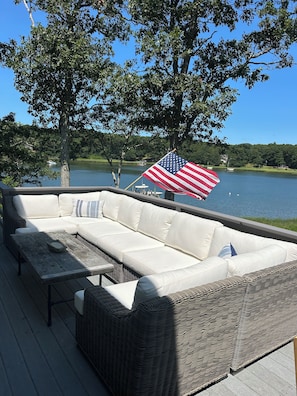 Eine Terrasse mit einer Rattan-Couch, einem Holztisch und einer amerikanischen Flagge.