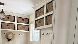 A white storage unit with shelves and hooks, a bench, and a small window. - Waterfront Orleans Oasis with a Private Deep Water Dock (Orleans)