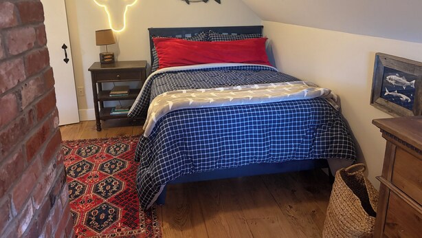A bedroom with a bed, a neon deer head light, a fish decoration, a rug, and a wooden floor. - Waterfront Orleans Oasis with a Private Deep Water Dock (Orleans)