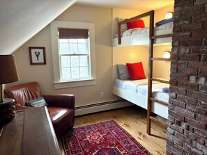 A room with a bunk bed, a leather chair, a patterned rug, a window with blinds, and a brick wall. - Waterfront Orleans Oasis with a Private Deep Water Dock (Orleans)