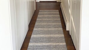 A hallway with a wooden staircase, a white door, and a patterned rug. - Waterfront Orleans Oasis with a Private Deep Water Dock (Orleans)