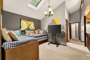 Ein gemütliches Zimmer mit einem Bett, einem Fernseher und einer Wandmalerei.