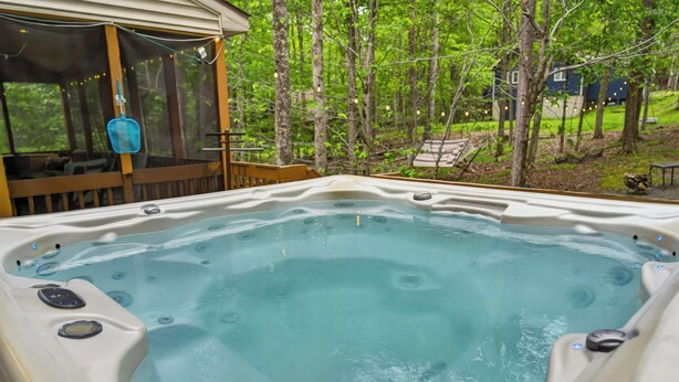 Jacuzzi con terraza de madera y vista a zona boscosa.