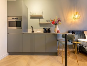 A modern kitchen with grey cabinets, a built-in oven, and a small island with a sink. - Studio RustUit by Interhome (Koudekerke)