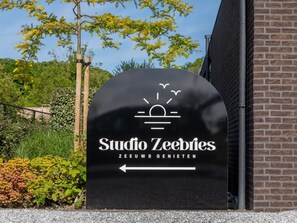 A black sign with white text for 'Studio Zeebries' and a directional arrow. - Studio RustUit by Interhome (Koudekerke)