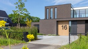 Ein modernes Gebäude mit Ziegelverkleidung, einem großen Fenster und einer Tür mit der Nummer 16.