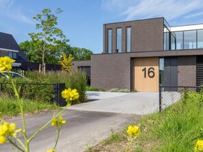 A modern building with a brick facade, a large window, and a door marked with the number 16. - Studio RustUit by Interhome (Koudekerke)