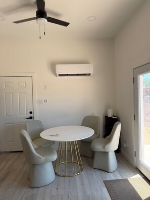 Ein stilvolles Zimmer mit rundem Tisch, zwei Stühlen, Deckenventilator und Klimaanlage.