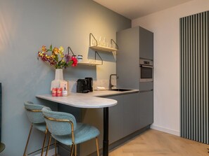 A modern kitchen with a built-in oven, a sink, and a small bar area with two chairs. - Studio ZeeRust by Interhome (Koudekerke)