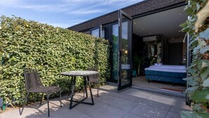 A modern house with a glass door leading to a bedroom with a blue bed. - Studio ZeeRust by Interhome (Koudekerke)