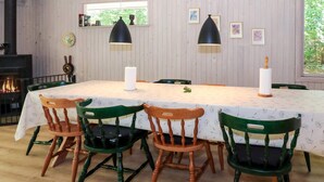 A dining room with a long table, four chairs, two pendant lights, a fireplace, and framed pictures on the wall. - 8 Person Holiday Home in Hadsund (Hadsund)