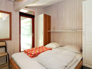 A bedroom with a bed, a chair, a wardrobe, and a door leading to an outdoor area. - 8 Person Holiday Home in Hadsund (Hadsund)