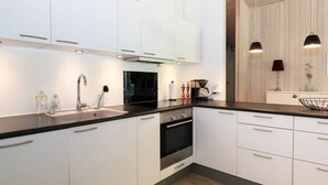 A modern kitchen with white cabinets, a black countertop, stainless steel appliances, and pendant lighting. - 8 Person Holiday Home in Hadsund (Hadsund)