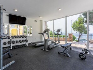 Ein Fitnessraum mit Laufbändern, Kurzhanteln und einer Trainingsbank.
