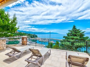 Eine Terrasse mit Liegestühlen mit Blick auf einen Yachthafen und ein Gewässer.