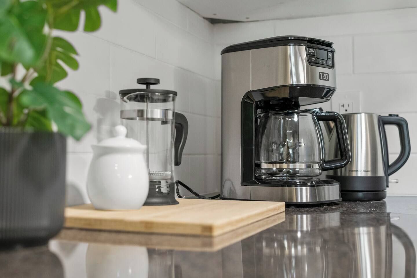 A kitchen with a coffee maker, a glass carafe, and a kettle on the counter.