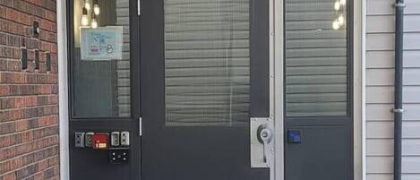 Une porte coulissante noire dotée d’un clavier de sécurité et d’un judas.