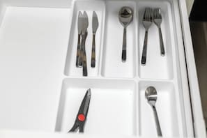 Eine Schublade mit Fächern, die verschiedene Besteckteile wie Gabeln, Löffel und ein Messer enthalten.