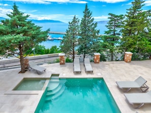A swimming pool with lounge chairs, a view of the sea, and trees. - Palace Paulina 3B / HR-10315-04 by Interhome (Novi Vinodolski)