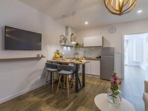 Una cocina moderna con zona de comedor, televisor montado en la pared y refrigerador.