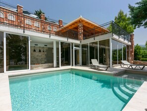 Una casa moderna con piscina, ventanas amplias y un patio cubierto.
