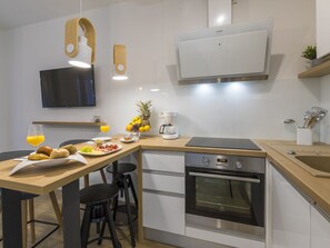 A modern kitchen with a wooden countertop, a coffee maker, a fruit bowl, and a TV mounted on the wall. - PALACE PAULINA 2B / HR-10322-01 by Interhome (Novi Vinodolski)