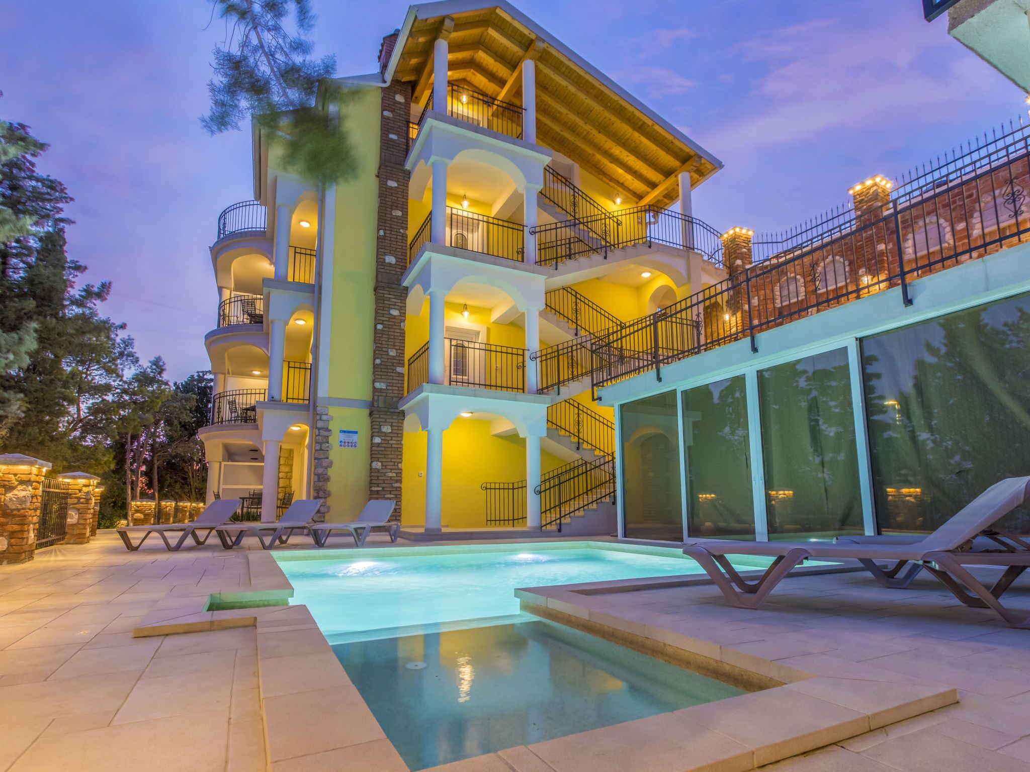 A multi-story hotel with a swimming pool, outdoor seating, and a balcony with a railing.
