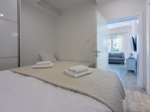 A modern bedroom with a large bed, a bedside table, and a view into the living area. - Palace Paulina 1B - 6+2 / HR-10380-01 by Interhome (Novi Vinodolski)