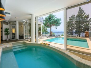 A swimming pool with a view of the sea, a covered patio area, and a glass door leading to an indoor space. - Palace Paulina 1B - 6+2 / HR-10380-01 by Interhome (Novi Vinodolski)