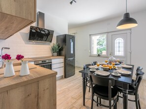 A modern kitchen with a dining area, a black refrigerator, and a dining table set for breakfast. - Palace Paulina 1B - 6+2 / HR-10380-01 by Interhome (Novi Vinodolski)